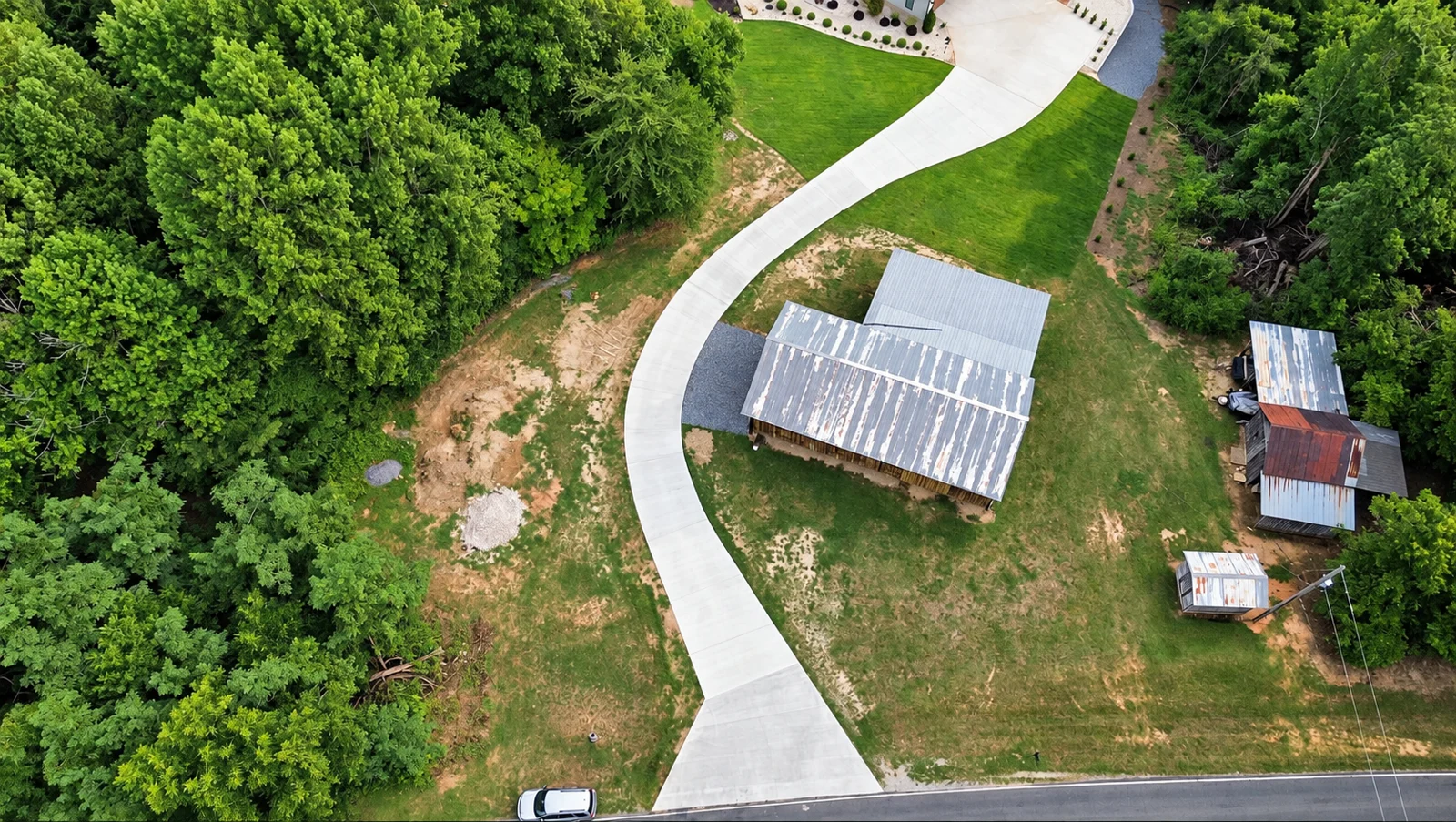 Sweeping concrete driveway through a wooded property